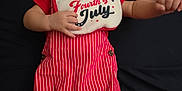 Liam is registered to the contest to win money with this photo: baby, bib, blanket, child, clothing, cute, expression, fabric, face, indoors, infant, looking_at_camera, lying_down, newborn, person, red, small_hands, soft, striped, white