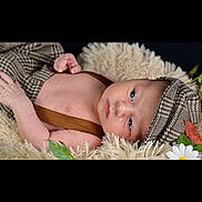 Kurtys participe au concours pour gagner de l'argent avec cette photo : baby, infant, hat, clothing, blanket, face, person, flower, leaf, nature, cute, portrait, lying_down, suspenders, soft_texture, cozy, young, skin, expression, indoor