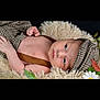 baby, infant, hat, clothing, blanket, face, person, flower, leaf, nature, cute, portrait, lying_down, suspenders, soft_texture, cozy, young, skin, expression, indoor