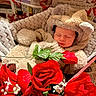 baby, sleeping, bear_costume, blanket, roses, red_flowers, flower_bouquet, newspaper, heart_drawings, cozy, cute, infant, soft_toy, portrait, resting, indoor, closeup, adorable, child, peaceful