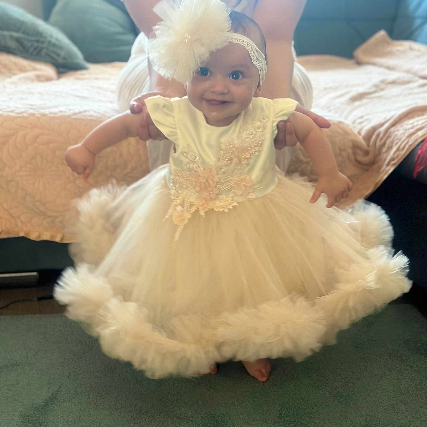 Darya a rejoint le concours — aidez-le/la à gagner de superbes lots ! adult_hands, baby, carpet, celebration, child, couch, cute, dress, floor, flower, happy, headband, holding, indoor, infant, person, portrait, smiling, tulle, white_dress