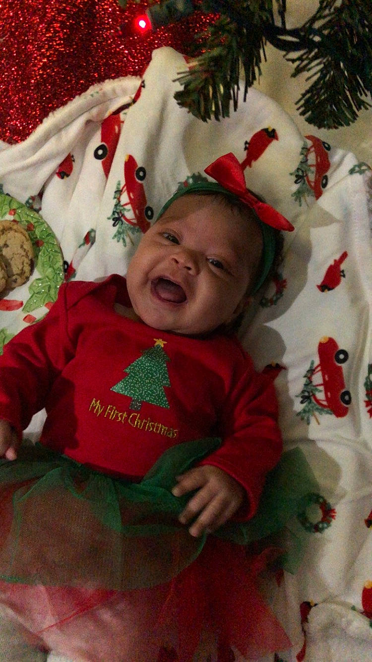 Xylah is registered to the contest to win money with this photo: baby, baby_toddler_clothing, carmine, child, christmas, christmas_decoration, christmas_ornament, event, fictional_character, happy, head, holiday, lap, leaf, linens, person, room, sleeve, smile, toddler