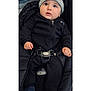 baby, child, face, hat, beanie, nike, jacket, black_clothing, car_seat, seatbelt, bundle, curious_expression, indoors, person, infant, cute, small_hands, looking_up, warm_clothing, footwear