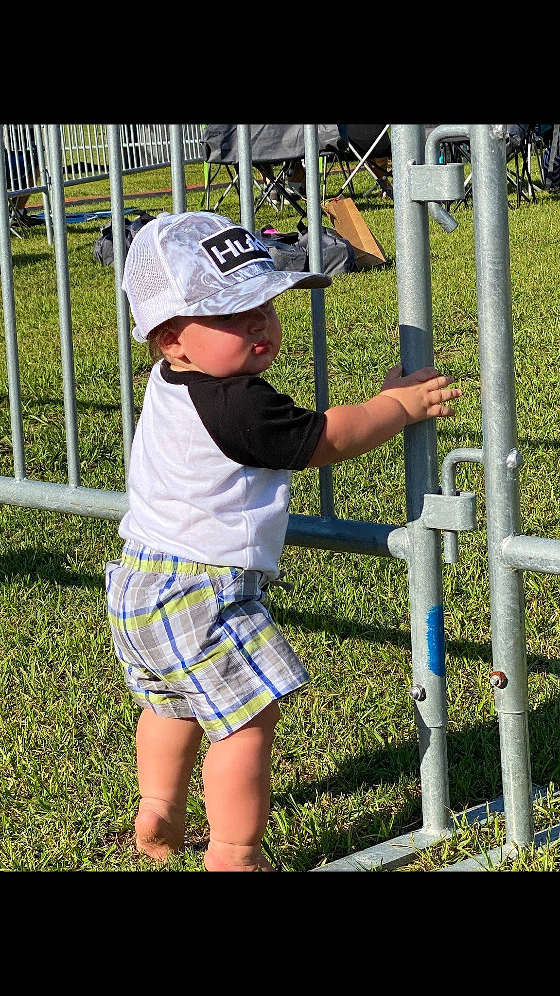 Gabe is registered to the contest to win money with this photo: baseball_cap, cap, child, electric_blue, fence, fun, grass, hat, headwear, leisure, outdoor_play_equipment, pattern, people_in_nature, person, play, recreation, shade, shorts, sun_hat, t_shirt