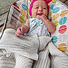 baby, infant, child, smiling, happy, portrait, face, pink_bow, headband, hand, finger, blanket, bouncer, baby_seat, patterned_fabric, outdoor, wooden_deck, colorful, sitting, safe