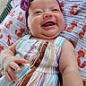 baby, infant, child, smiling, happy, portrait, face, headband, bow, dress, striped_clothing, blanket, animal_pattern, lying_down, outdoor, seated, adorable, close_up, relaxed, photography
