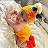 Ismael a rejoint le concours — aidez-le/la à gagner de superbes lots ! baby, infant, crocheted_hat, yellow_outfit, orange_socks, cute, lying_down, blanket, indoor, portrait, child, knitted_clothing, headwear, face, expression, soft_lighting, cozy, home, curious, newborn
