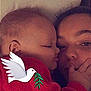 Christian is registered to the contest to win money with this photo: child, baby, infant, adult, face, close_up, portrait, cuddling, red_blanket, dove_sticker, sticker, kissing, touching_face, cozy, indoor, bed, pillow, family, love, sleepy