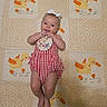 Genevieve joined the competition — help win amazing prizes! baby, bib, bow, child, close_up, duck_pattern, ducks, fabric, feet, gingham, hands, happy, indoors, infant, lying_down, nursery, portrait, quilt, red_dress, smiling