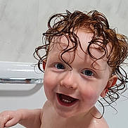 Kodi is registered to the contest to win money with this photo: child, toddler, bathtub, bath, water, wet_hair, curly_hair, smile, happy, skin, blue_eyes, person, indoor, bathroom, marble_wall, playful, cute, head, face, young
