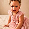 toddler, child, curly_hair, pink_dress, bow, flower_embroidery, cute, portrait, indoor, soft_lighting, baby, sitting, hands, face, looking, expression, cozy, texture, young_child, innocence
