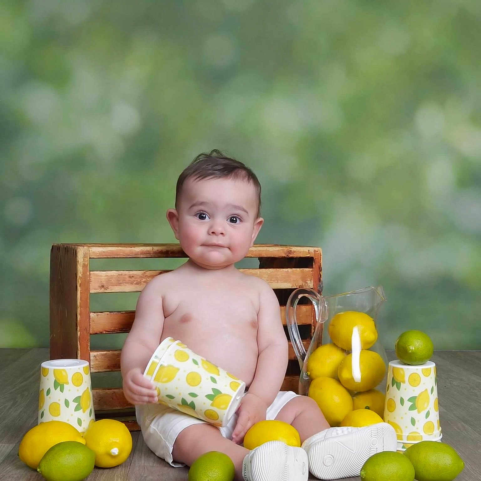 Karam is registered to the contest to win money with this photo: baby, child, colorful, crate, cup, curious_expression, fresh, fruit, indoor, lemon, lime, pitcher, playful, portrait, sitting, smiling, still_life, white_shoes, white_shorts, wooden_floor