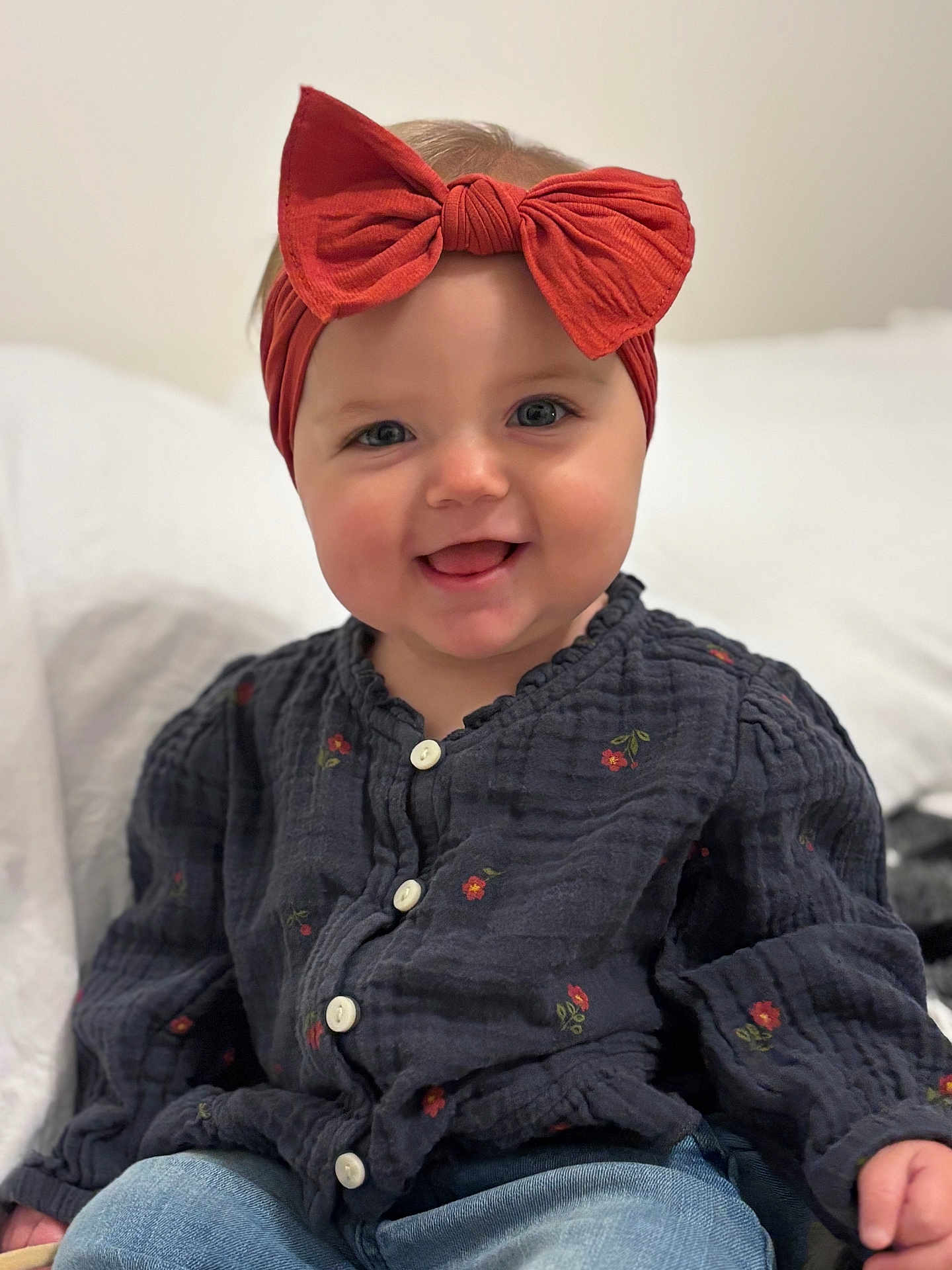 Carter joined the competition — help win amazing prizes! baby, child, smile, happy, headband, bow, clothing, button_up, floral, jeans, sitting, portrait, cute, indoor, person, face, head, skin, baby_girl, closeup