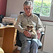 Boby a rejoint le concours — aidez-le/la à gagner de superbes lots ! man, person, puppy, dog, pet, sitting, chair, glasses, shirt, jeans, office, home, window, sunlight, printer, desk, cabinet, radiator, indoors, portrait