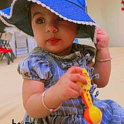 Asees Kaur is registered to the contest to win money with this photo: accessory, baby, background, blue_dress, blue_hat, bracelet, child, clothing, curious, cute, expression, face, floor, hope, indoor, person, portrait, sitting, toddler, toy