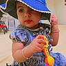 accessory, baby, background, blue_dress, blue_hat, bracelet, child, clothing, curious, cute, expression, face, floor, hope, indoor, person, portrait, sitting, toddler, toy