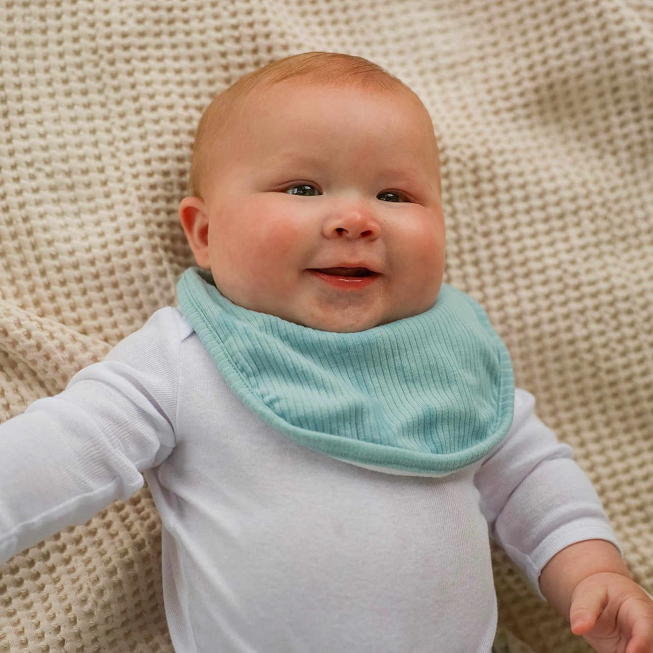 Daniel is registered to the contest to win money with this photo: baby, bib, blanket, cheeks, child, closeup, cute, denim_pants, hand, happy, human, indoors, infant, laying_down, portrait, skin, smiling, soft_light, texture, white_clothing