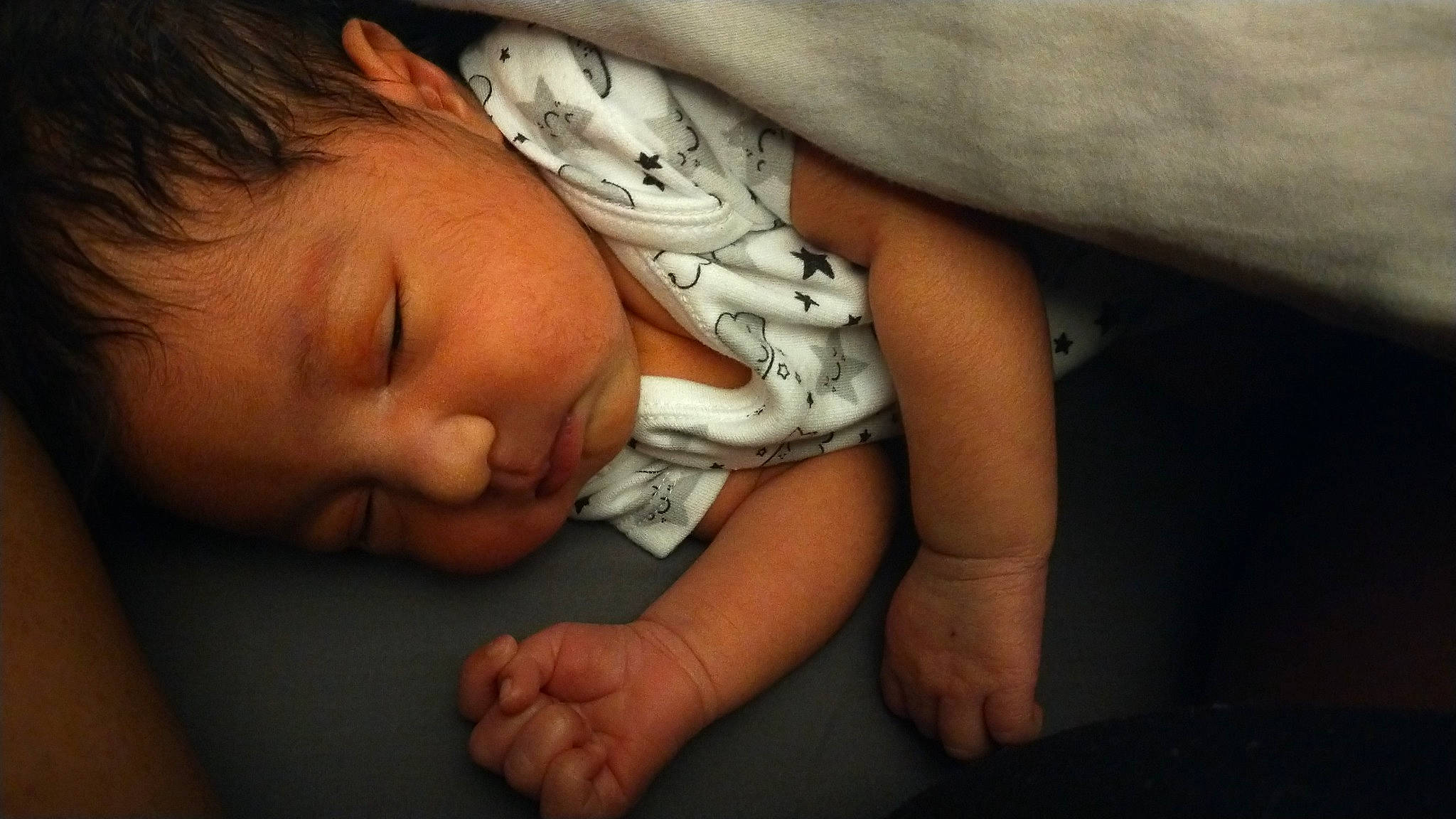 Olympia is registered to the contest to win money with this photo: arm, baby, baby_toddler_clothing, cheek, child, comfort, elbow, finger, flash_photography, gesture, hand, human_body, linens, mouth, nail, nose, person, skin, sleeve, thumb