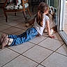 Ulysse participe au concours pour gagner de l'argent avec cette photo : child, dog, indoor, tile_floor, glass_door, jeans, white_shirt, brown_hair, long_hair, footwear, furniture, chair, curiosity, companion, pet, resting, casual_clothing, home, natural_light, flooring