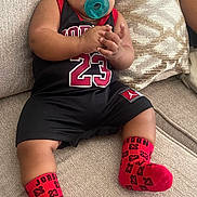 Raylan joined the competition — help win amazing prizes! baby, infant, pacifier, socks, clothing, couch, pillow, hand, face, person, indoor, relaxing, cute, child, sporty, red, black, comfortable, apparel, portrait