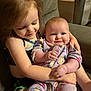 child, baby, smiling, couch, holding, love, cute, family, indoor, comfort, pajamas, butterfly_pattern, happy, toddler, sitting, affection, arm, young_girl, infant, closeup