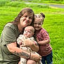 woman, baby, child, outdoor, grass, greenery, family, smile, tattoo, casual_clothing, baby_clothes, shorts, tshirt, nature, portrait, happy, hugging, person, road, summer