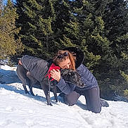 Millie participe au concours pour gagner de l'argent avec cette photo : woman, dog, snow, evergreen_trees, outdoor, winter, hug, pet, animal, cold_weather, blue_sky, jacket, leash, nature, friendship, kneeling, canine, sunlight, tree, winter_clothing