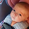 baby, infant, child, car_seat, harness, seatbelt, portrait, close_up, wide_eyes, calm, vehicle_interior, sitting, padded_seat, pink, orange, gray, floral_clothing, safety, indoors, photograph