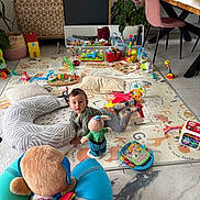 Rihan Nils a rejoint le concours — aidez-le/la à gagner de superbes lots ! baby, child, toy, playmat, cushion, living_room, plant, furniture, floor, colorful, indoor, child_playing, mirror, puzzle, chair, table, window, book, stuffed_animal, decor