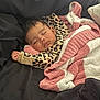 baby, sleeping, blanket, leopard_print, cozy, infant, child, black_background, soft_texture, resting, cute, peaceful, earring, pink, white, striped_blanket, face, clothing, portrait, comfort