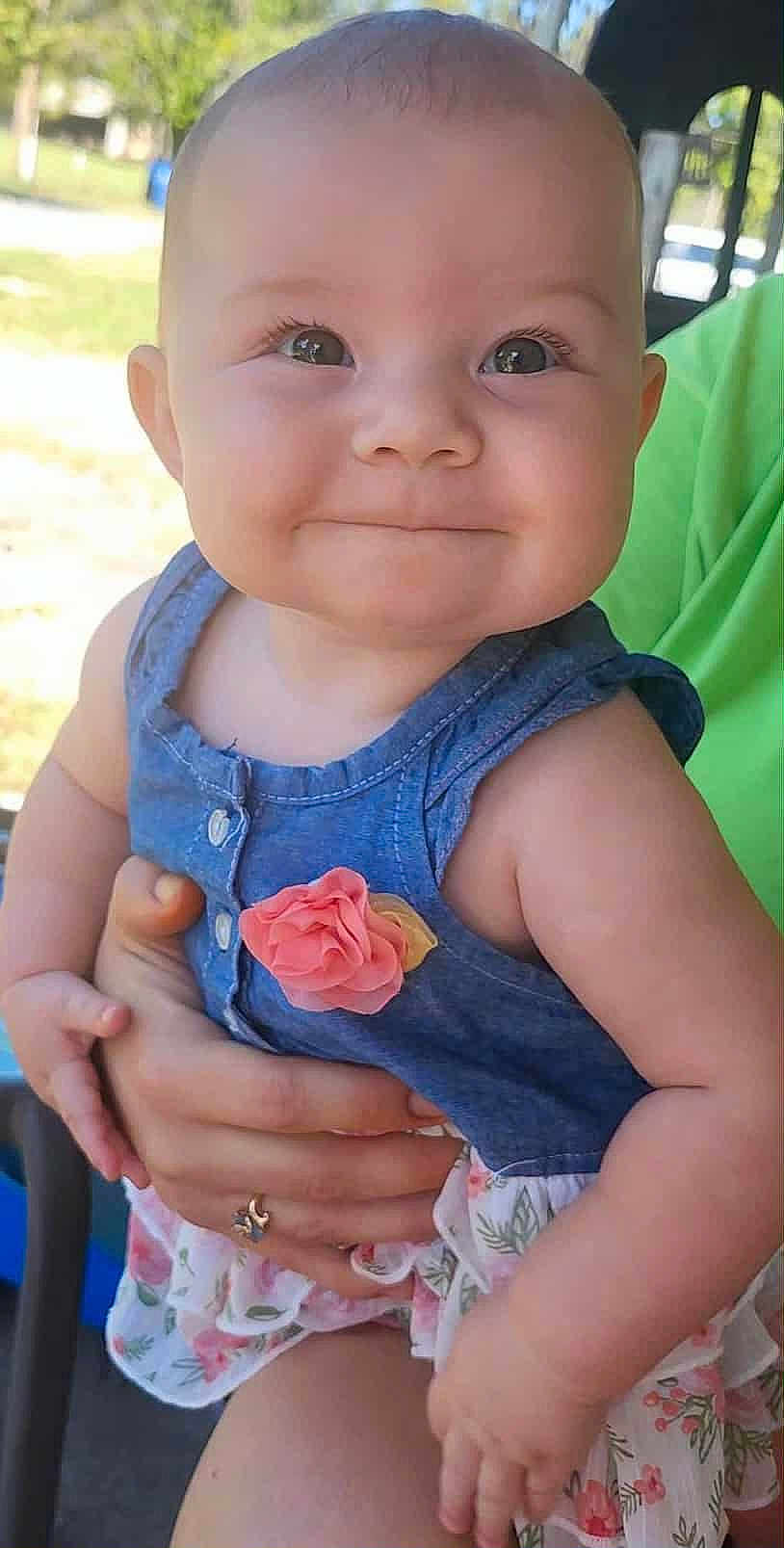 Leenna joined the competition — help win amazing prizes! baby, child, smiling, face, eyes, dress, flower, hand, person, skin, outdoor, sunlight, holding, cute, infant, happy, portrait, closeup, human, clothing