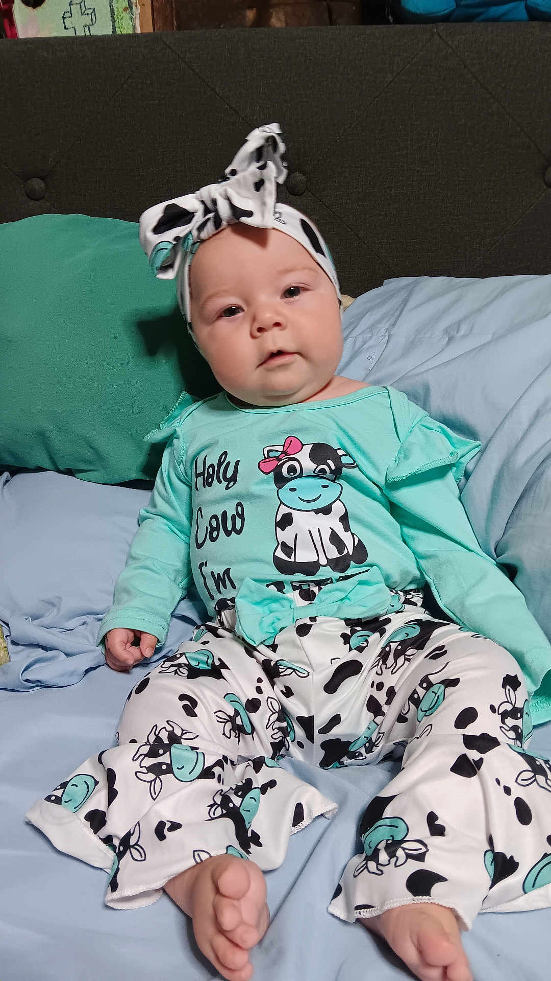 Leenna joined the competition — help win amazing prizes! baby, child, infant, cute, cow_print, headband, clothing, pajamas, bed, pillow, blue, green, feet, sitting, face, person, indoors, soft, comfortable, expression
