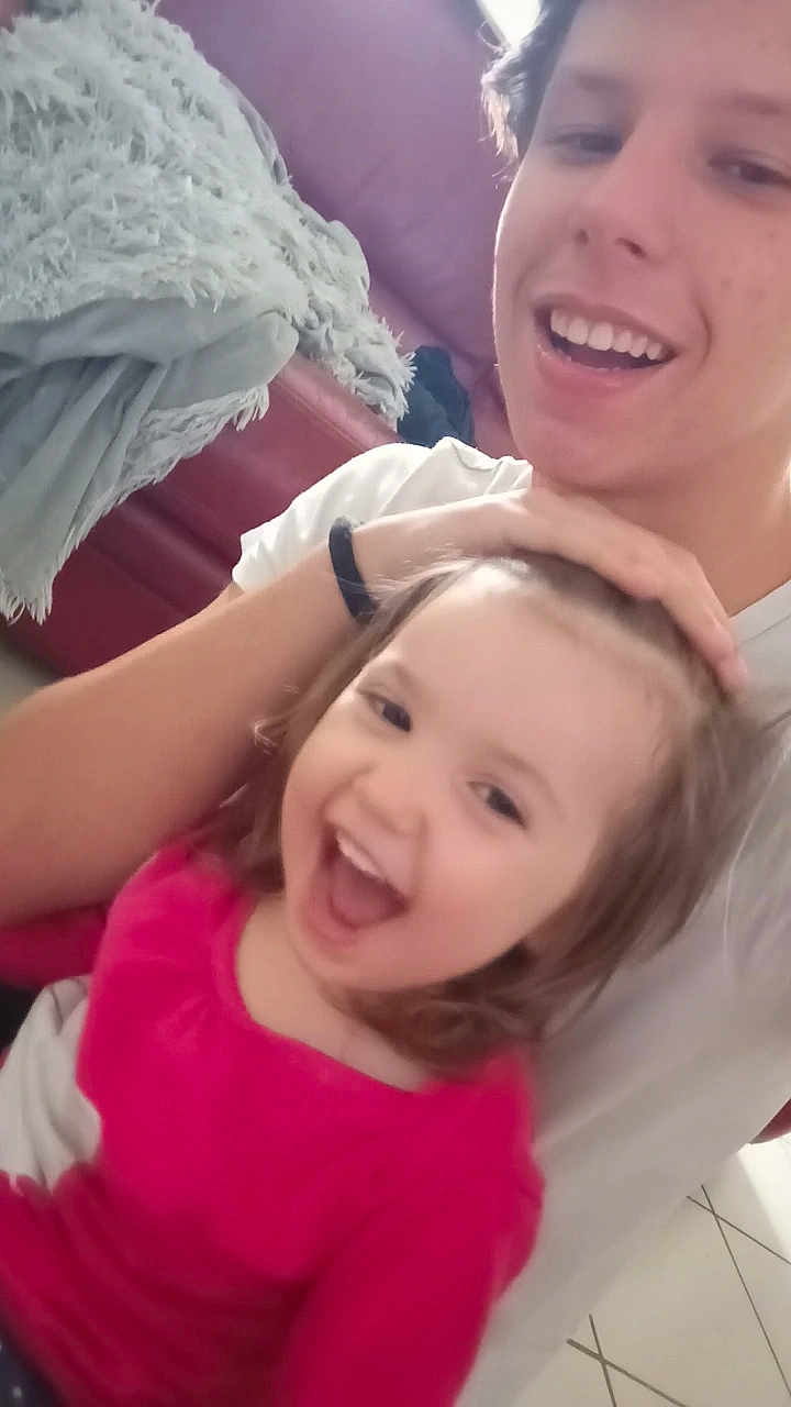 Wendy participe au concours pour gagner de l'argent avec cette photo : child, person, smile, laughing, indoor, couch, blanket, white_shirt, happy, family, sibling, living_room, cozy, casual, young, joy, playful, cute, tiled_floor, hand