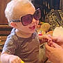 toddler, child, sunglasses, toy_car, laughing, indoor, hands, person, clothing, hair, play, happy, face, furniture, stuffed_toy, background, floor, interaction, casual, smile