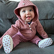 Talia joined the competition — help win amazing prizes! baby, baby_shoes, buttoned_hoodie, child, clothing, couch, cute, face, footwear, gray_couch, happy, heart_pattern, hood, indoor, infant, pink_hoodie, portrait, seated, small_child, smiling
