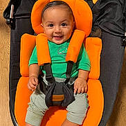 Zayden joined the competition — help win amazing prizes! baby, child, smiling, orange_cushion, green_shirt, striped_pants, baby_seat, wooden_floor, black_fabric, happy, infant, sitting, indoor, cute, portrait, childcare, baby_toy, star_shaped_toy, comfort, face
