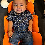 Zayden is registered to the contest to win money with this photo: baby, child, smiling, blue_shirt, denim_shorts, orange_cushion, plush_star, plush_moon, seat, indoor, happy, person, cute, infant, portrait, clothing, furniture, wood_floor, sitting, young