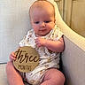 baby, infant, armchair, onesie, plaque, wooden_sign, three_months, milestone, cute, chubby_cheeks, sitting, indoors, kitchen, cabinet, countertop, homedecor, child, person, portrait, smile