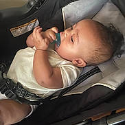 Jacob joined the competition — help win amazing prizes! baby, child, pacifier, stroller, infant, white_clothing, hand, face, seat_belt, curly_hair, indoor, closeup, cute, resting, young_child, portrait, relaxing, car_seat, baby_toy, baby_boy