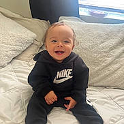 Jayden joined the competition — help win amazing prizes! baby, child, smiling, sitting, hoodie, nike, clothing, bed, pillow, blanket, indoor, cute, happy, person, foot, light, window, cozy, infant, casual