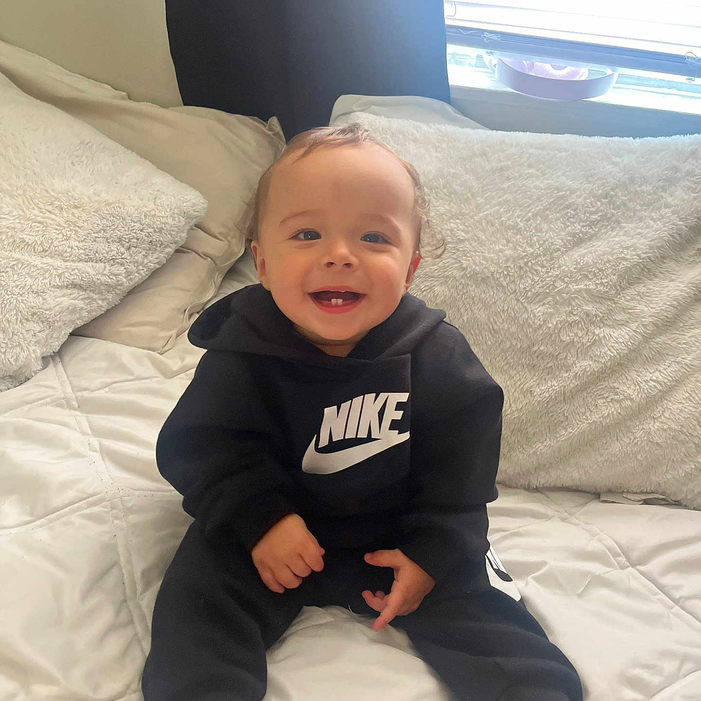 Jayden joined the competition — help win amazing prizes! baby, child, smiling, sitting, hoodie, nike, clothing, bed, pillow, blanket, indoor, cute, happy, person, foot, light, window, cozy, infant, casual