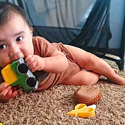 Jadiel is registered to the contest to win money with this photo: baby, toy, car, carpet, indoor, child, chewing, playing, floor, cute, person, infant, hand, foot, brown_clothing, furniture, soft, carpet_texture, closeup, home