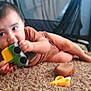 baby, toy, car, carpet, indoor, child, chewing, playing, floor, cute, person, infant, hand, foot, brown_clothing, furniture, soft, carpet_texture, closeup, home