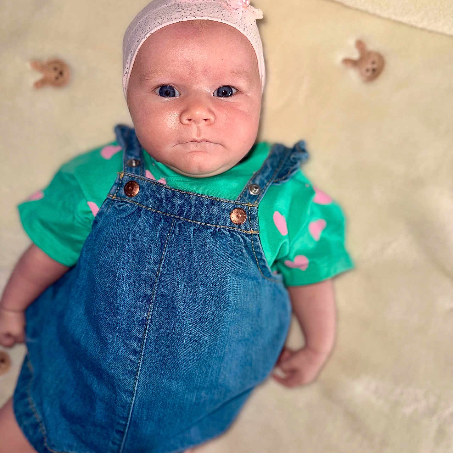Livia a rejoint le concours — aidez-le/la à gagner de superbes lots ! baby, blanket, blue_eyes, bunny_pattern, child, clothing, cute, denim_dress, expression, face, green_shirt, headband, indoors, infant, laying_down, person, pink_flowers, portrait, skin, soft_texture