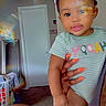 baby, carpet, child, colorful, cute, door, face, hair_bows, hand, holding, indoor, laundry_basket, nails, onesie, person, rainbow_light, reflection, smile, striped_clothing, toddler