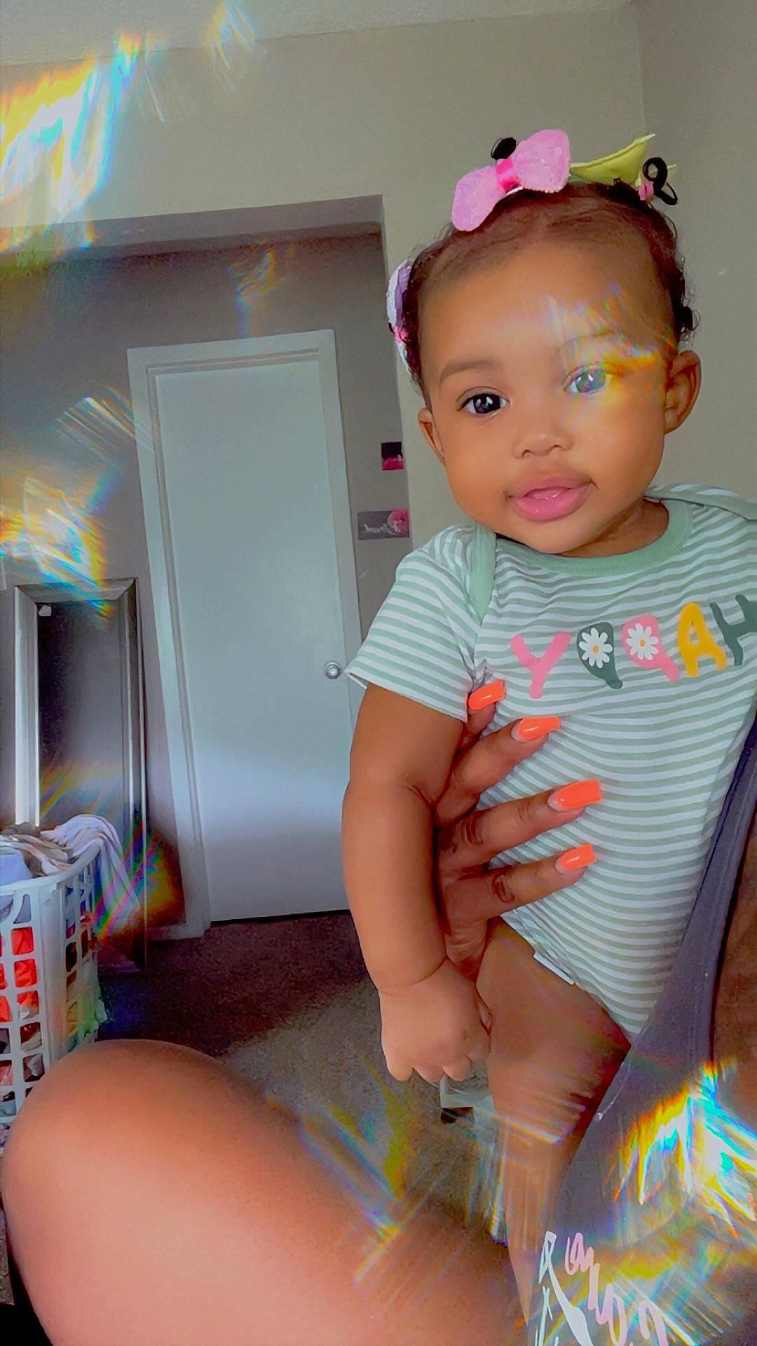 Legacy is registered to the contest to win money with this photo: baby, bow, carpet, child, colorful, cute, door, hair_accessory, hand, happy, indoor, laundry_basket, nails, person, portrait, prism_effect, room, smiling, striped_clothing, toddler