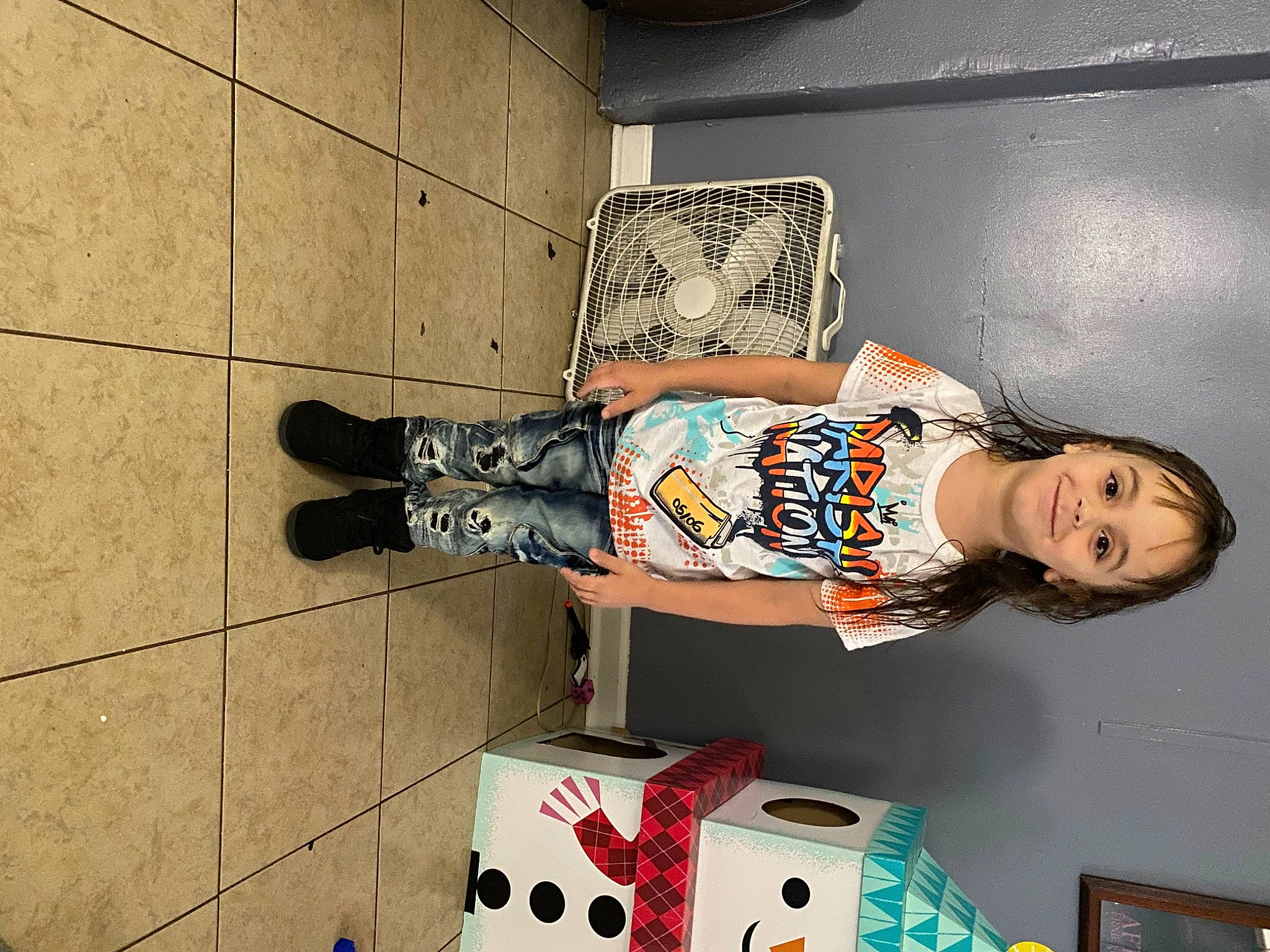 Julian is registered to the contest to win money with this photo: art, boot, carmine, child, concrete, denim, dress, eyewear, fashion_design, flooring, fun, human_leg, joy, leg, pattern, person, sitting, t_shirt, thigh, visual_arts