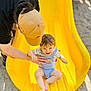 child, toddler, slide, yellow_slide, playground, adult, cap, smile, fun, outdoor, sand, summer, happy, support, casual_clothing, person, baby, play, joy, recreation