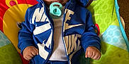Kamari is registered to the contest to win money with this photo: baby, infant, pacifier, curly_hair, blue_clothing, nike, baby_seat, colorful, indoor, child, cute, sitting, young_child, portrait, clothing, relaxed, small_hands, fun, casual, comfort