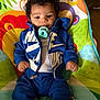 Kamari is registered to the contest to win money with this photo: baby, infant, pacifier, curly_hair, blue_clothing, nike, baby_seat, colorful, indoor, child, cute, sitting, young_child, portrait, clothing, relaxed, small_hands, fun, casual, comfort